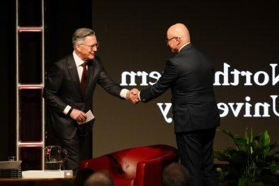 Two men shake hands on a stage